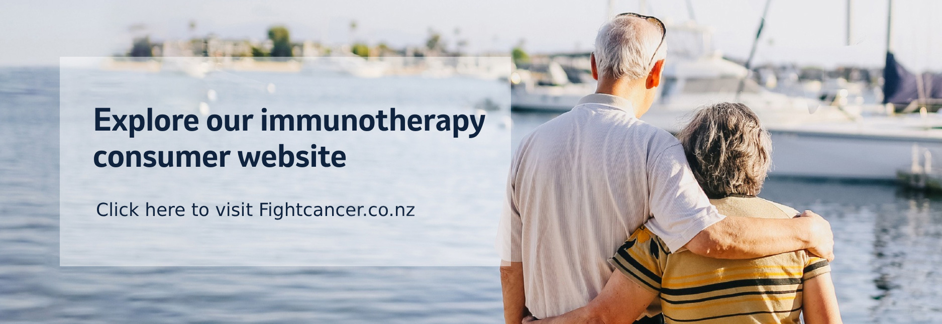 Elderly man and woman with their arms around each other, looking out onto a marina.