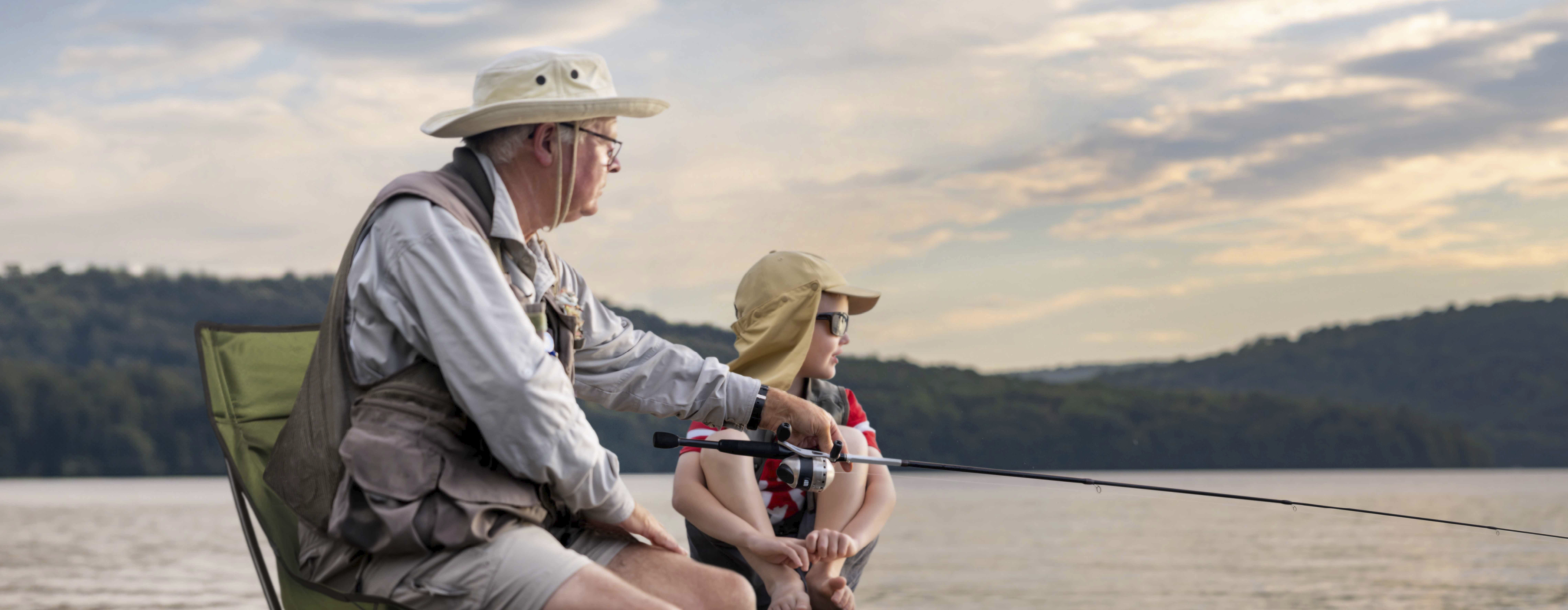 Image of a grandfather and grandson sitting on a dock fishing