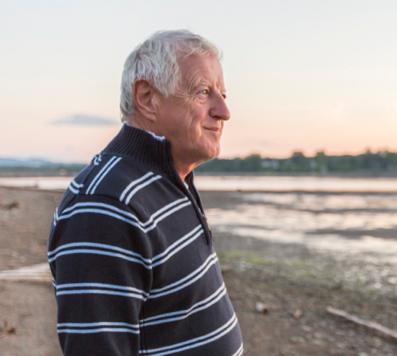Image of a hypothetical male patient standing on a beach looking out to the ocean.